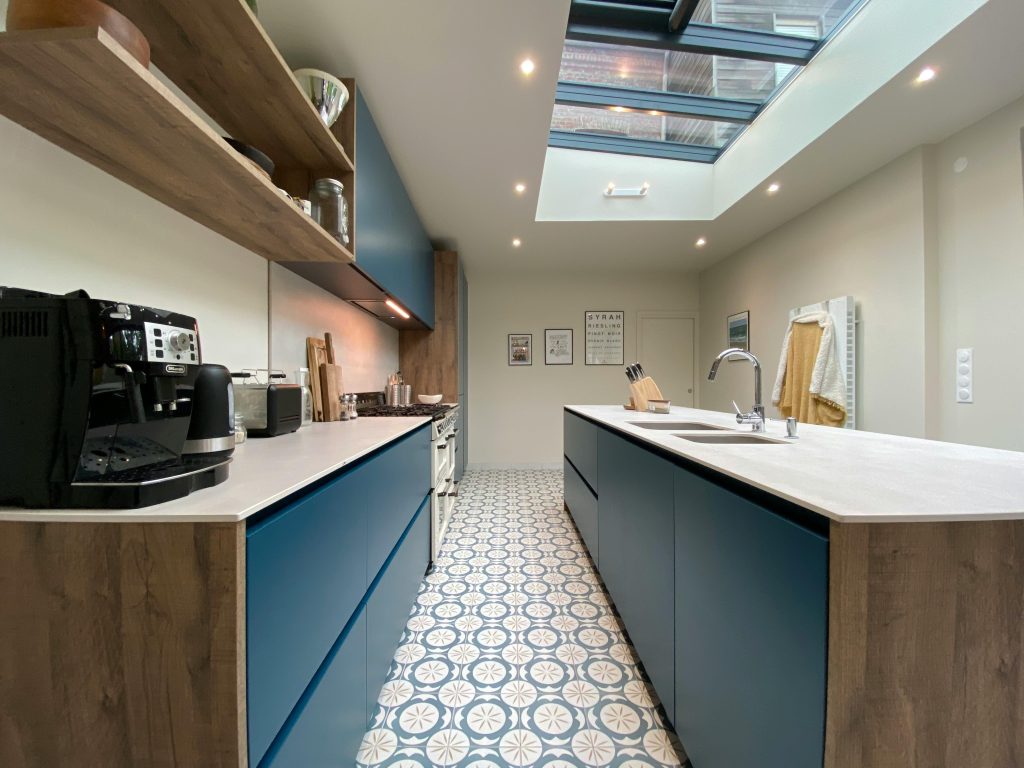 Contemporary kitchen design featuring blue cabinets, a skylight, and patterned floor tiles.
