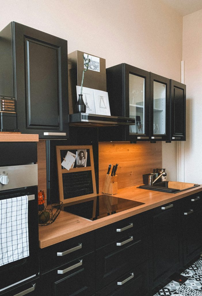 Sleek modern kitchen setup with black cabinets and wooden countertop.