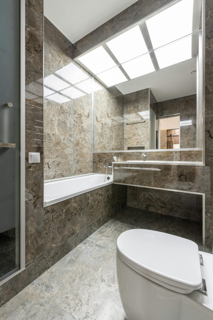 Sleek marble-tiled bathroom with modern fixtures and ample lighting.